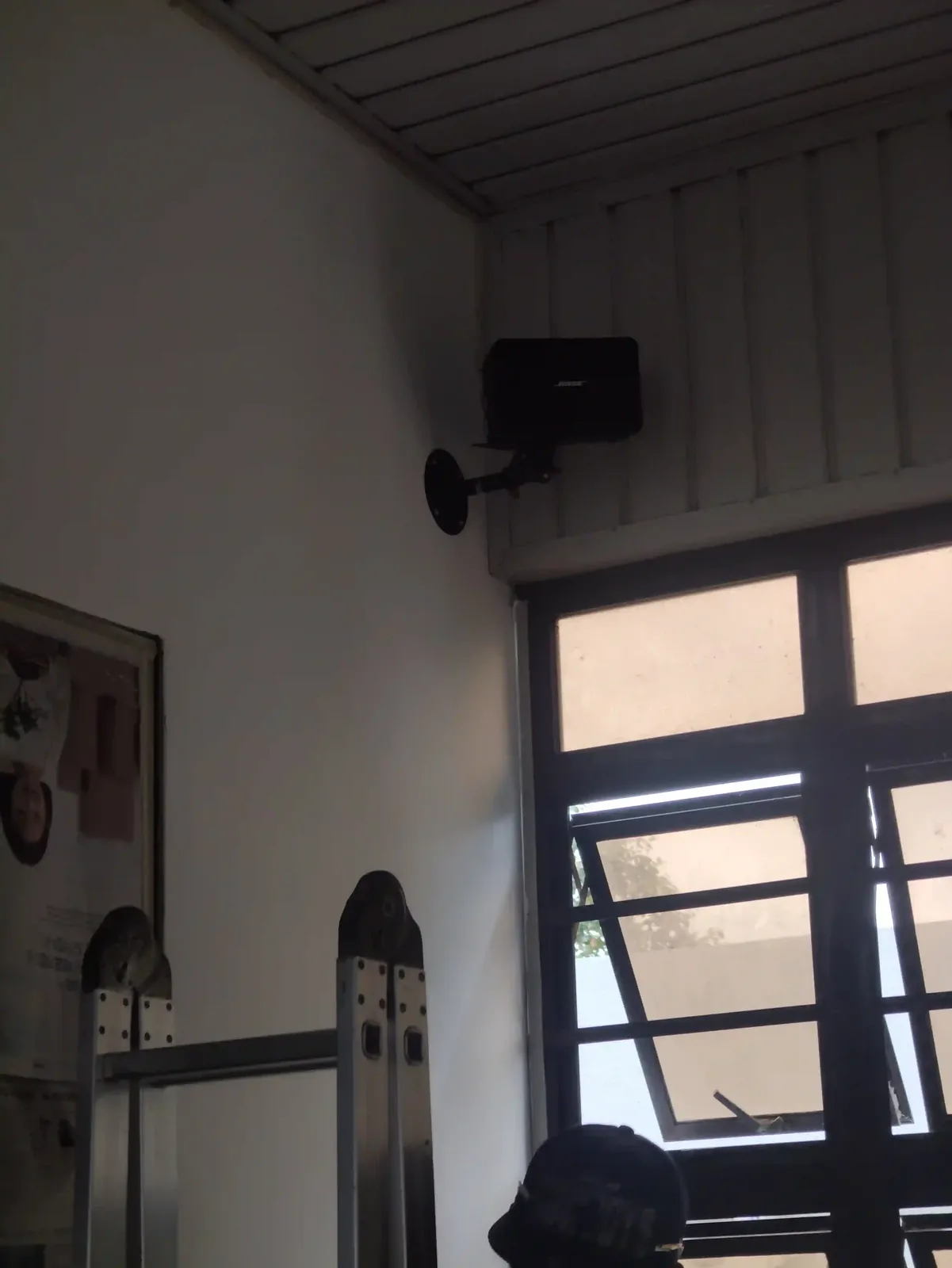 A wall-mounted Bose speaker on a bracket, an aluminium ladder alongside.